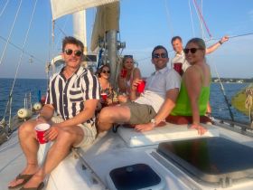 A lively group enjoys drinks aboard a sailboat, capturing the essence of fun and celebration on the water.