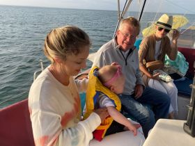 A joyful family moment aboard a boat, with a baby in a life jacket being held by a smiling adult — perfect for creating cherished memories on the water.
