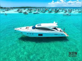 A stunning aerial view of a luxurious yacht cruising through crystal-clear turquoise waters, surrounded by numerous boats — perfect for a day of adventure on the water.