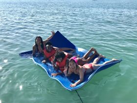 A lively group enjoys a day on a floating mat in clear waters, showcasing the fun and excitement of summer adventures on the water.