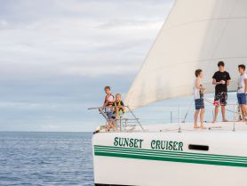 A group of children and teens enjoy a sailing adventure aboard the 'Sunset Cruiser,' capturing the joy of youth and the beauty of the open water.