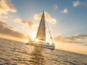 A beautiful sunset sailing experience aboard the 'Sunset Cruiser,' with guests enjoying the scenic views and warm glow of the evening sky.
