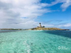 A stunning view of a picturesque island with a lighthouse, surrounded by crystal-clear turquoise waters — an ideal destination for boat tours and scenic adventures.