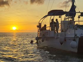 A group of divers enjoys a stunning sunset aboard their boat, creating a perfect backdrop for an unforgettable ocean adventure.