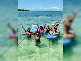 A lively group of friends enjoys a fun day in the water, celebrating with floating mats and playful poses — perfect for summer adventures and memorable outings.