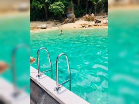 A person enjoys a refreshing swim in the crystal-clear waters of a secluded beach, perfect for a relaxing day on the water.