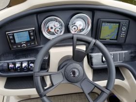 A detailed view of the helm and console of a boat, showcasing the navigation and entertainment systems — perfect for understanding the boat's features and controls.
