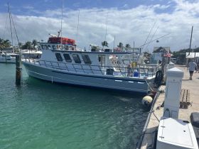 A fishing boat docked at the marina with a child visible on board, showcasing a vibrant day on the water.