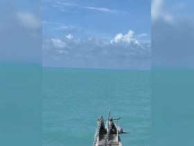 A serene view of a boat's bow with chains, set against a backdrop of turquoise waters and a clear blue sky, perfect for showcasing the beauty of nautical adventures.