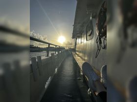 A serene view from inside a boat, showcasing a cozy seating area with a beautiful sunset in the background — perfect for relaxing moments on the water.