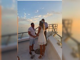 A couple exchanges vows during a romantic wedding ceremony on a boat at sunset, creating a picturesque backdrop for their special day.