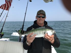 A proud angler displays his catch while fishing on the open ocean, showcasing the thrill of a successful day on the water.