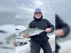 A young angler proudly displays his catch while fishing on the ocean, showcasing the thrill of a successful day out on the water.