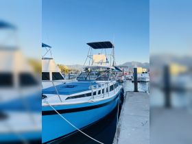 A vibrant blue yacht docked at the marina, showcasing its sleek design against a clear sky — perfect for a day on the water.