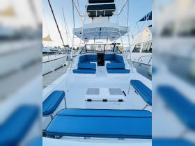 A spacious interior view of a boat's cabin featuring comfortable blue seating and a central helm area, perfect for relaxing or navigating on the water.