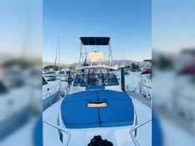 A clear view of a well-maintained boat docked at the marina, showcasing its sleek design and inviting blue cushions — perfect for relaxing on the water.