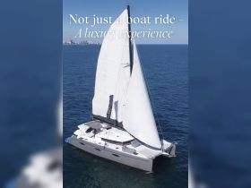 An aerial view of a luxurious catamaran sailing on clear waters, showcasing the elegance of a premium boating experience.