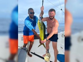 Two anglers proudly display their catch aboard a fishing boat, showcasing the thrill of deep-sea fishing adventures.