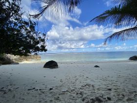 A serene beach scene featuring soft white sand and clear turquoise waters under a beautiful sky — an ideal destination for relaxation and exploration.
