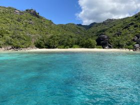 A stunning view of a secluded beach surrounded by lush greenery and crystal-clear waters, perfect for island hopping and relaxation.