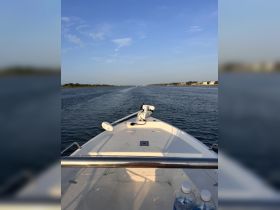 A view from the front of a center console boat cruising through calm waters, showcasing the serene landscape and clear blue skies.