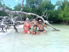 A joyful family enjoys a fun day swimming in shallow waters surrounded by mangroves, creating lasting memories in a beautiful beach setting.