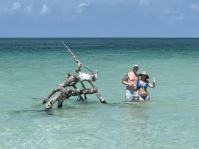 A couple enjoys a refreshing drink while standing in shallow turquoise waters, creating a perfect beach moment for relaxation and celebration.