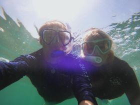 Two snorkelers capture a fun underwater selfie, showcasing the vibrant marine life and clear waters — a perfect moment for adventure enthusiasts.