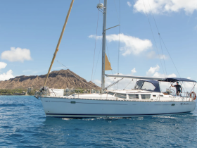 A sailboat navigates the clear waters with a stunning mountain backdrop, showcasing the beauty of ocean adventures.