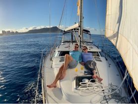 A couple relaxes on the deck of a yacht, enjoying drinks and the stunning ocean view — an ideal setting for romantic getaways or sunset cruises.