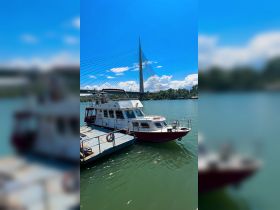 A picturesque view of a boat docked by the water, with a striking bridge in the background, perfect for showcasing waterfront adventures.