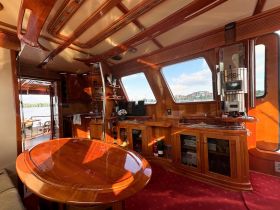 A beautifully designed interior of a boat featuring polished wood finishes, a spacious table, and a cozy seating area, perfect for relaxing while enjoying the views.