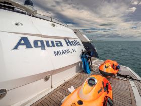 The Aqua Holic yacht showcases vibrant jet skis and snorkeling gear on its deck, perfect for adventurous water activities in Miami.