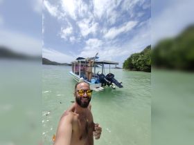 A joyful moment captured with friends enjoying a sunny day by the boat in clear waters — perfect for summer adventures and beach outings.