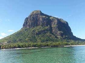 A stunning view of a majestic mountain rising above a tranquil coastline, perfect for showcasing the natural beauty of the area.
