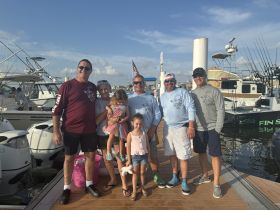 A cheerful group of family and friends poses at the dock, ready for a day of fishing and fun on the water.