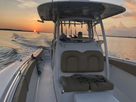 A serene view from the helm of a boat at sunset, showcasing the comfortable seating and tranquil waters — perfect for evening cruises.