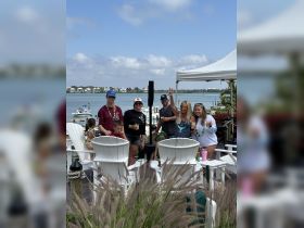 A lively group enjoys drinks and good company by the water, perfect for celebrating special moments or just relaxing in a beautiful setting.