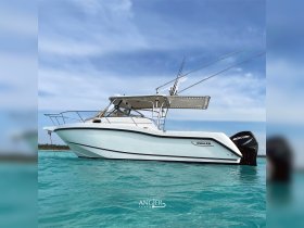 A sleek Whaler boat glides through clear turquoise waters, showcasing its elegant design and fishing capabilities — perfect for adventurous outings on the sea.