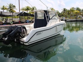 A sleek Whaler boat docked in calm waters, showcasing its elegant design and reflection in the water — perfect for fishing or leisure outings.