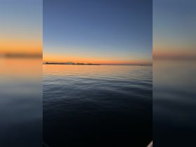 A serene sunset view over calm waters, showcasing the beautiful coastline and creating a perfect backdrop for evening boat trips.