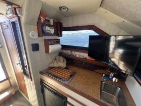 Interior view of a boat's kitchen area, showcasing the helm, storage, and amenities — perfect for preparing meals while on the water.