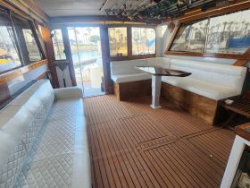 Interior view of a spacious boat cabin featuring comfortable seating and a polished wooden floor, ideal for relaxing during fishing trips or day cruises.