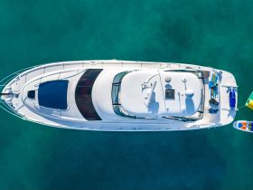 A stunning aerial view of a sleek yacht cruising through crystal-clear waters, showcasing its elegant design and onboard equipment.