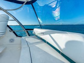 A serene view of the interior seating area of a boat, showcasing comfortable lounge space and panoramic windows overlooking the tranquil waters.