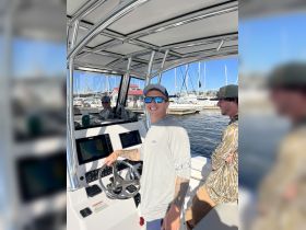 A cheerful captain takes the helm of a boat, showcasing the modern console and navigation equipment, perfect for a day on the water.