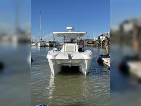 A sleek speedboat is docked at the marina, with crew members preparing for departure. The clear blue sky and surrounding boats create a vibrant nautical scene.