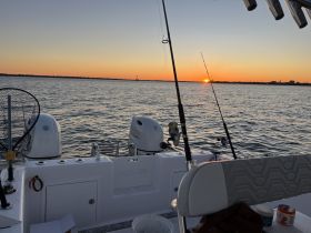 A serene sunset view from a fishing boat, showcasing the tranquil waters and fishing gear, perfect for a relaxing day on the water.