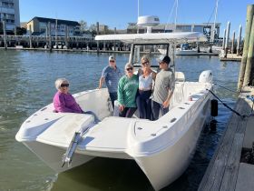 A cheerful group of friends poses on their boat at the dock, ready for a day of adventure on the water.