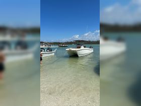 A lively scene at the beach with boats anchored in shallow waters, showcasing a fun day of boating and water activities.